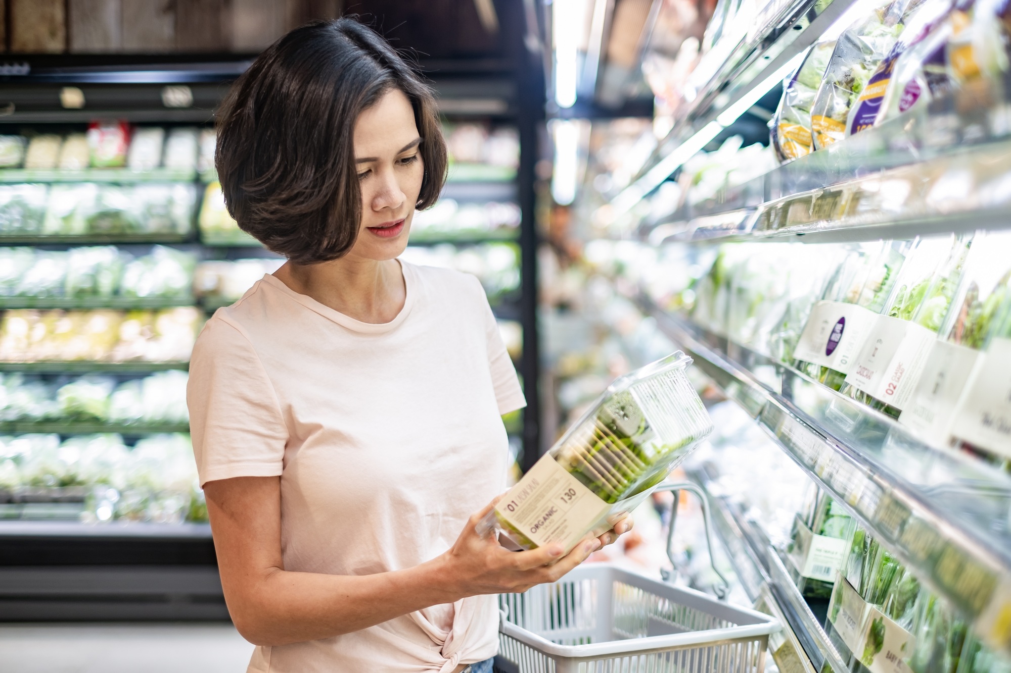 Young Asian beautiful woman holding grocery basket walking in supermarket.